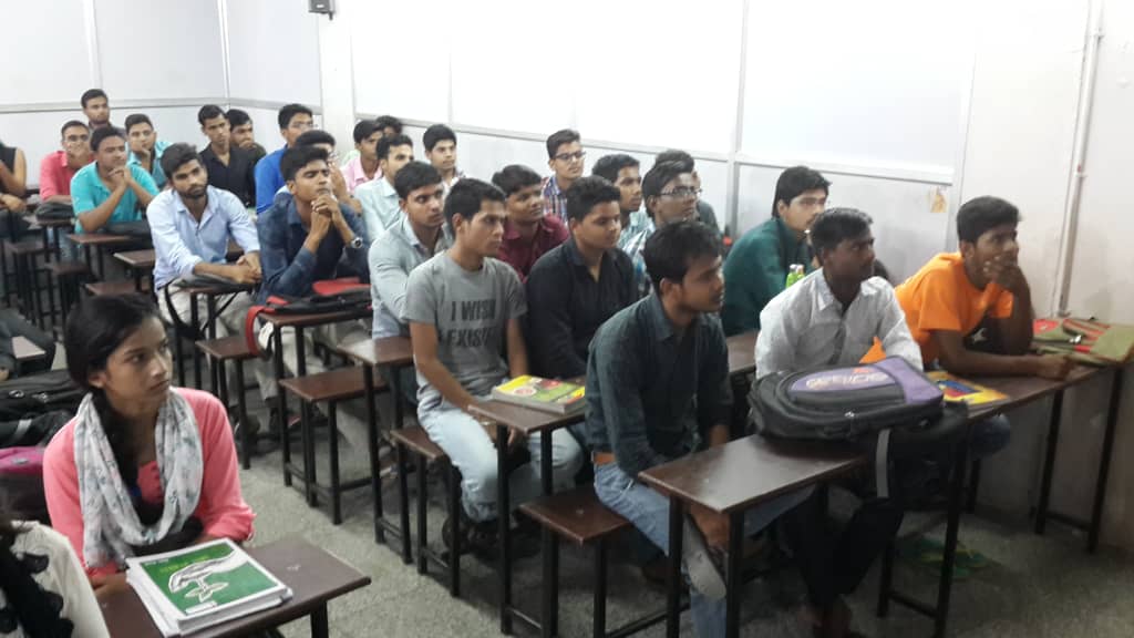 Students seated at wooden desks listening during a roadshow session