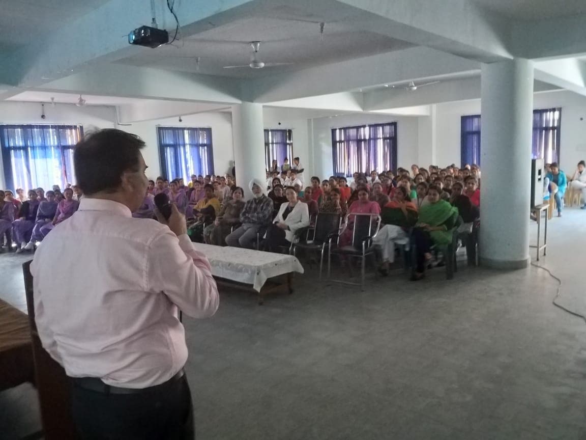 A speaker with a microphone addressing a full hall of seated students at a roadshow session