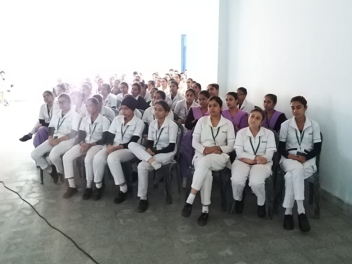 Rows of students in white uniforms seated together at a session